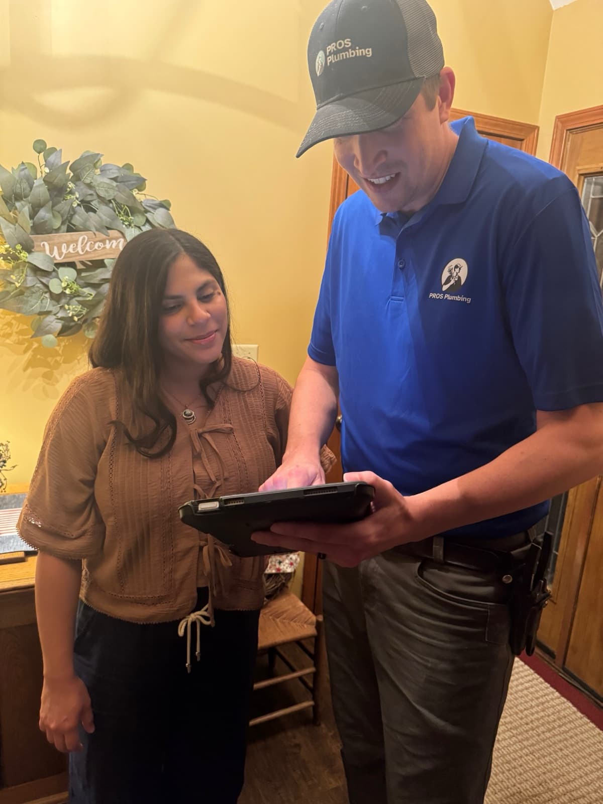 PROS Plumbing plumber reviewing pricing options with a homeowner on a tablet